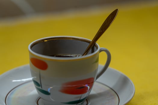 A golden spoon in a coffee mug. A mug in a saucer on a yellow background photo