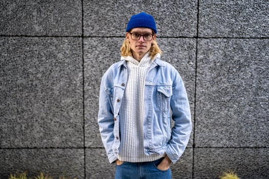 Blond long hair guy, scandinavian androgynous appearance in glasses standing on street. photo