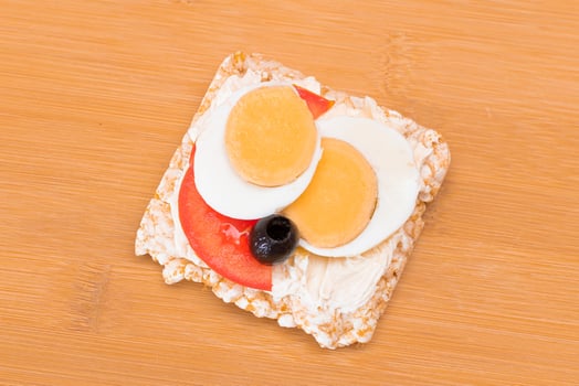 Rice Cake Sandwich with Tomato, Eggs and Olives on Bamboo Cutting Board. Easy Breakfast. Diet Food. Quick and Healthy Sandwiches. Crispbread with Tasty Filling. Healthy Dietary Snack photo