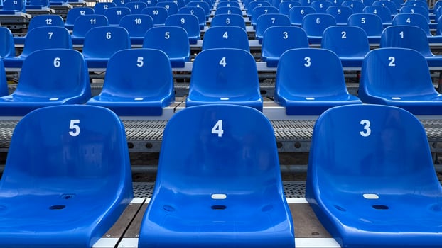 Multiple rows of empty blue stadium seats, each labeled with white numbers, lined up symmetrically, creating a repetitive pattern. The scene is orderly and structured. photo