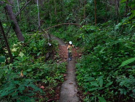 Asian girl hiking with backpack in rainy season and walking stick. photo