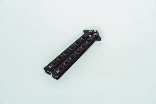 Partially open matte black balisong or butterfly knife isolated on white background. Close-up of a sharp balisong knife or butterfly knife in various positions on a white background photo