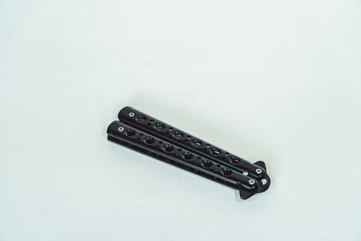 Partially open matte black balisong or butterfly knife isolated on white background. Close-up of a sharp balisong knife or butterfly knife in various positions on a white background photo