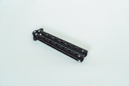 Partially open matte black balisong or butterfly knife isolated on white background. Close-up of a sharp balisong knife or butterfly knife in various positions on a white background photo