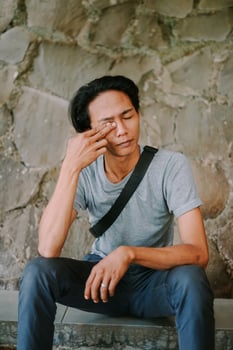 Southeast Asian man rubbing his eyes, captured in a candid momen photo