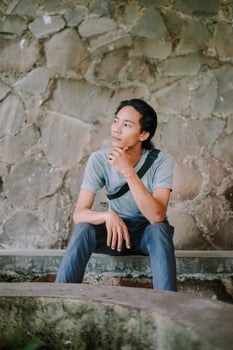 Young man sitting with hands clasped, looking at the camera with a serious expression photo