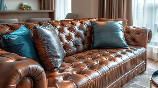 Close-up of a brown leather sofa with blue and silver pillows in a living room. photo