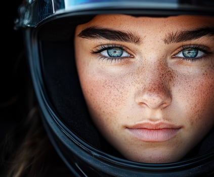 Young woman in a racing helmet with striking blue eyes, close-up photo