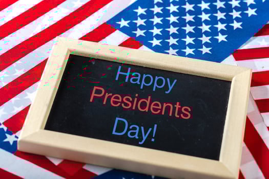 the text happy presidents day written in a chalkboard and a flag of the United States photo