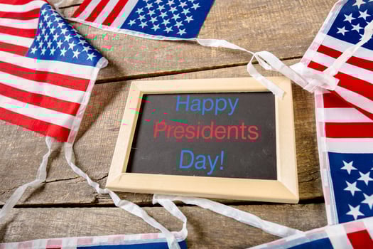 the text happy presidents day written in a chalkboard and a flag of the United States photo