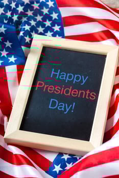 the text happy presidents day written in a chalkboard and a flag of the United States photo