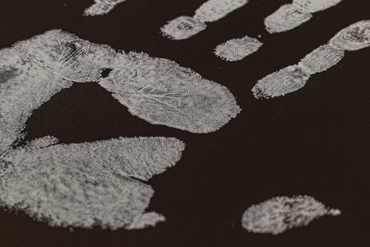 An angled view of a human handprint on black cardboard photo
