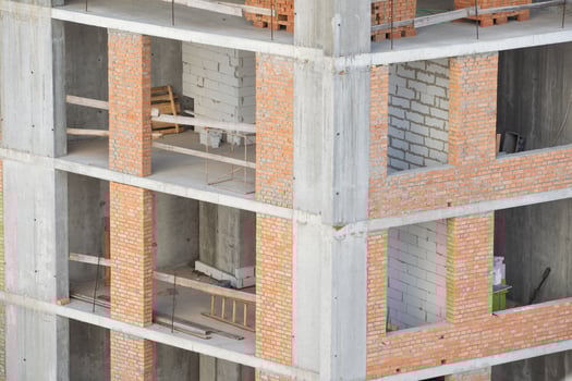 View of a large construction site with buildings under construction and multi-storey residential homes.Tower cranes in action on blue sky background. Housing renovation concept. Crane during formworks photo