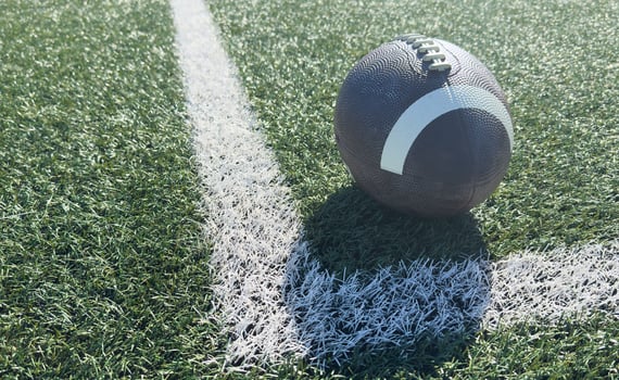 Close up of an american football on the field, players in the background photo