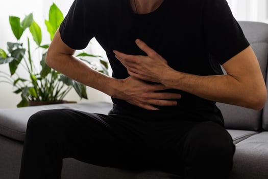 Man suffering stomach ache sitting on a couch in the living room at home photo