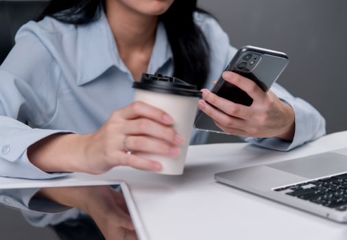 A woman holding a coffee cup and a cell phone photo
