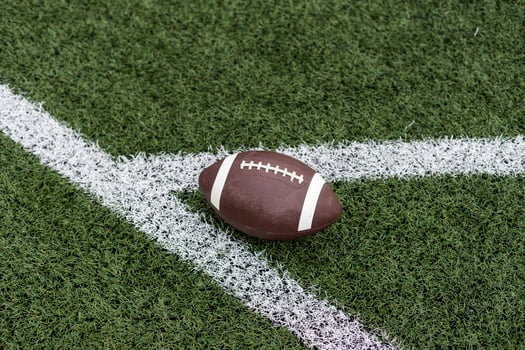 Close up view of an American Football sitting on a grass football field on the yard line. Generic Sports image photo
