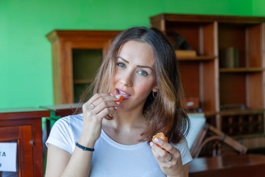 portrait of young beautiful woman is eating an orange in her house photo