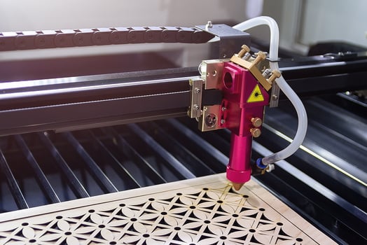 Laser engraving machine carves a design on a wooden surface photo
