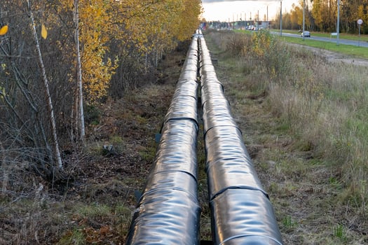 Insulated pipeline stretching through autumn landscape near highway photo