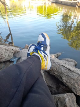 A person's feet on a rock near a body of water photo