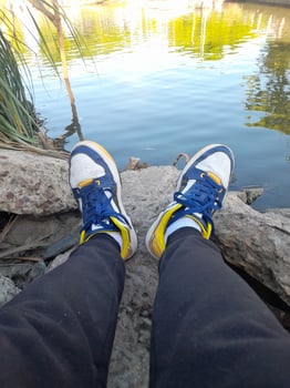 A person's feet standing on a rock next to a body of water photo