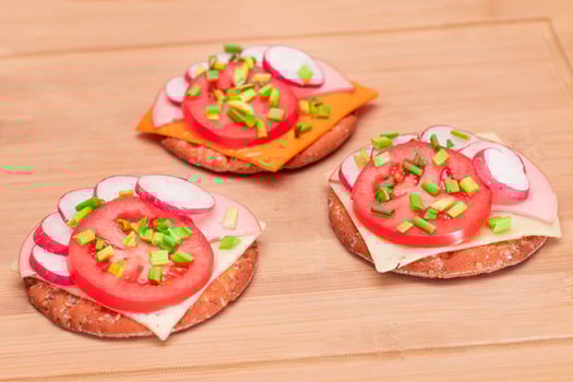 Crispy Cracker Sandwiches with Tomato, Sausage, Cheese, Green Onions and Radish on Cutting Board. Easy Breakfast. Quick and Healthy Sandwiches. Crispbread with Tasty Filling. Healthy Dietary Snack photo