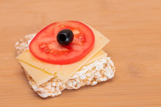 Rice Cake Sandwich with Tomato, Cheese and Olives on Bamboo Cutting Board. Easy Breakfast. Diet Food. Quick and Healthy Sandwiches. Crispbread with Tasty Filling. Healthy Dietary Snack photo