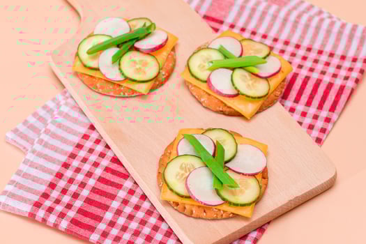 Light Breakfast. Quick and Healthy Sandwich. Fresh Cucumber and Radish with Green Onions and Cheese on Crispy Cracker on Wooden Cutting Board photo