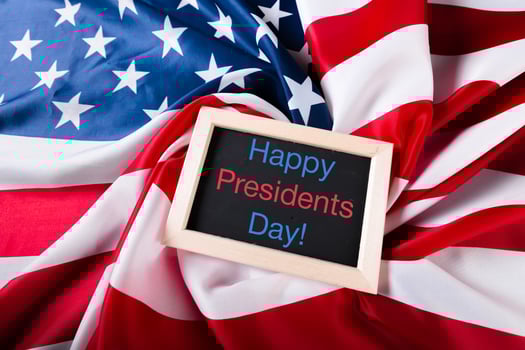 the text happy presidents day written in a chalkboard and a flag of the United States photo