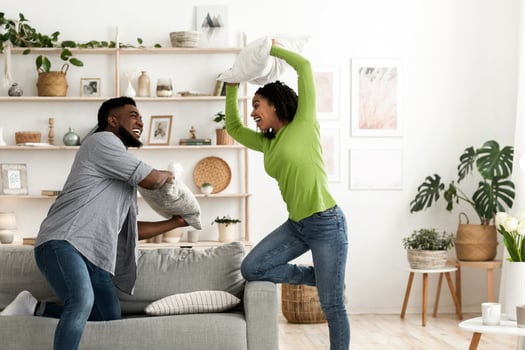 Playful african american couple fighting by pillows, fooling together at home, having fun in living room, copy space photo