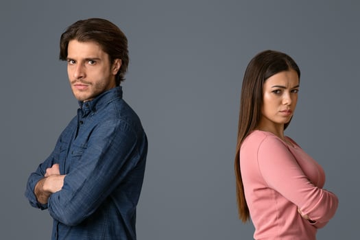 Break Up. Offended man and woman standing back to back with folded arms on light studio background and looking at camera, free space photo