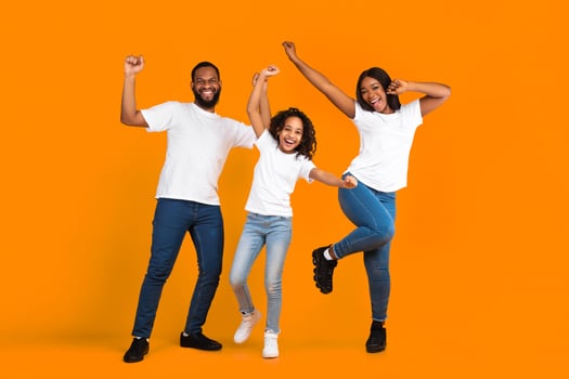 Having Fun. Full body length of excited young black family of three dancing and fooling around. Happy African American man, woman and girl enjoying favorite music together on yellow studio background photo
