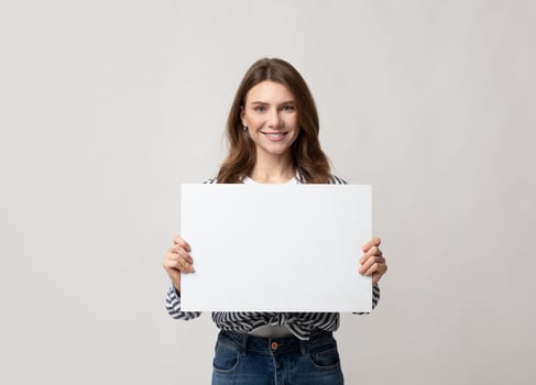 Beautiful Young Woman Holding Blank Placard With Copy Space For Advertisement. Smiling millennial lady demonstrating white empty billboard with place for text, standing over grey studio background photo