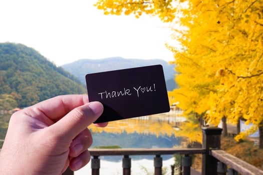 Thank You card in a hand against autumn landscape photo