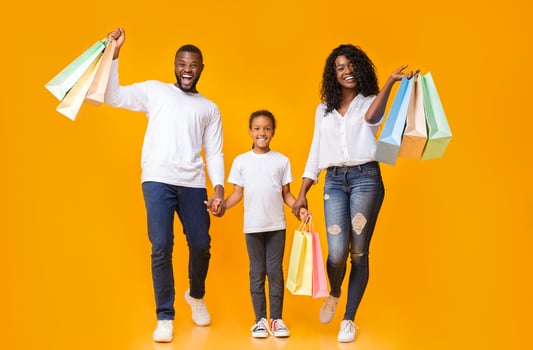 Family Shopping. African American Parents And Their Daughter Carrying Shopper Bags And Smiling Over Yellow Background, Copy Space photo