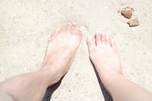Woman's and men's feet on the sand at the beach in the summer. photo