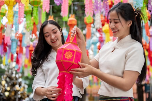 Two Asian women hold a lantern together, enjoying a traditional lantern festival at a temple. photo