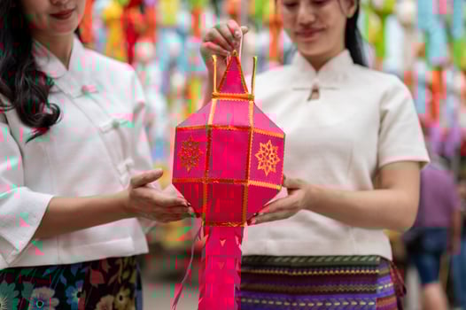 A close-up of two charming Asian women in traditional dresses hold a lantern together. photo