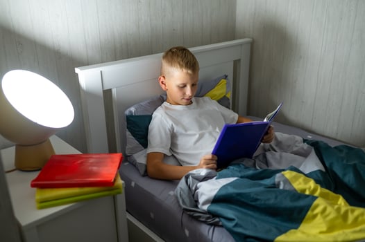 fair-haired teenage boy reading a book before bed photo