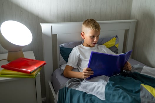 fair-haired teenage boy reading a book before bed photo