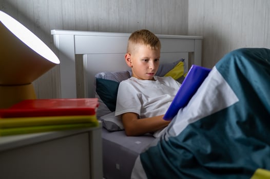 fair-haired teenage boy reading a book before bed photo