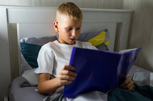 fair-haired teenage boy reading a book before bed photo