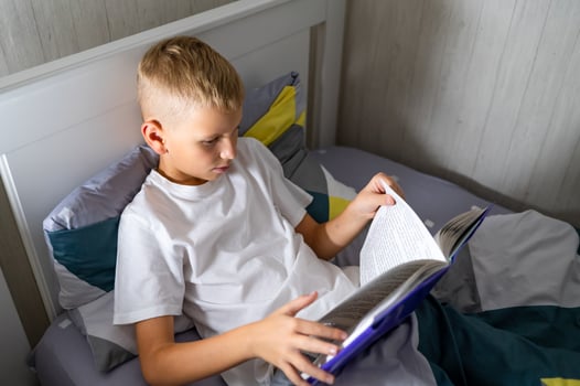 fair-haired teenage boy reading a book before bed photo