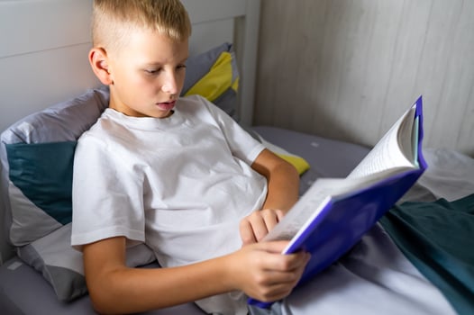 fair-haired teenage boy reading a book before bed photo