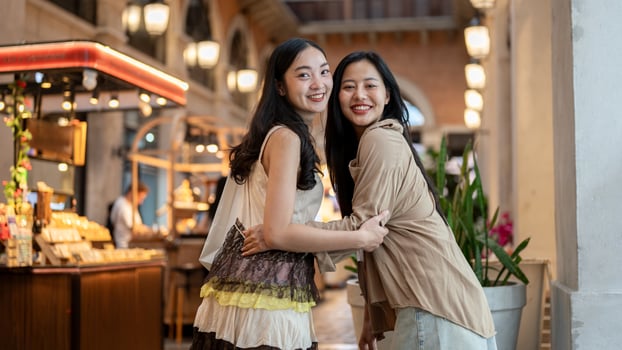 Two attractive Asian female friends enjoy shopping together at a mall, smiling at the camera. photo