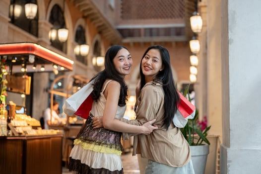 Two attractive Asian female friends enjoy shopping together at a mall, smiling at the camera. photo