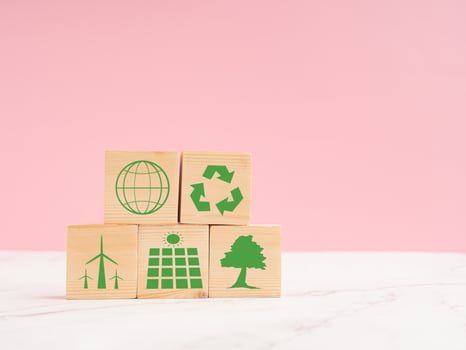 World Earth day concept. Wooden cubes with eco-friendly icons over a marble floor against a light pink background photo