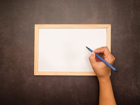 Hand holding chalk about to write something on a mini whiteboard photo