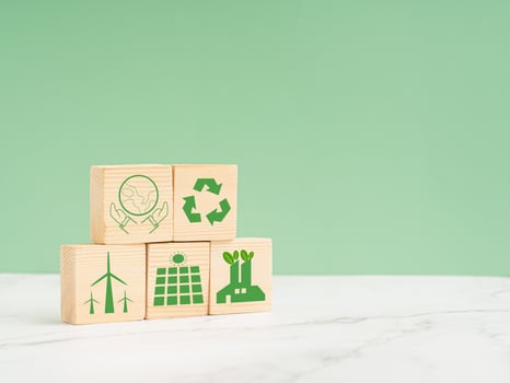 Net-zero greenhouse gas emissions target. Wooden cubes with green icons over a marble floor against a light green background photo